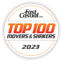 A logo showcasing "Fast Casual Top 100 Movers & Shakers 2023" in bold orange and black text within a circular design, highlighting the impact of leading QSR franchises.